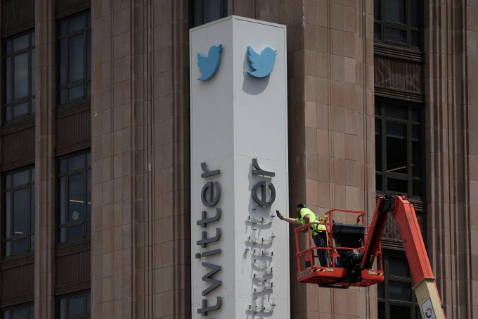 Nhân viên Twitter tháo dỡ bảng hiệu cũ sau khi Musk tuyên bố đổi tên mạng xã hội này thành X. Ảnh: Reuters